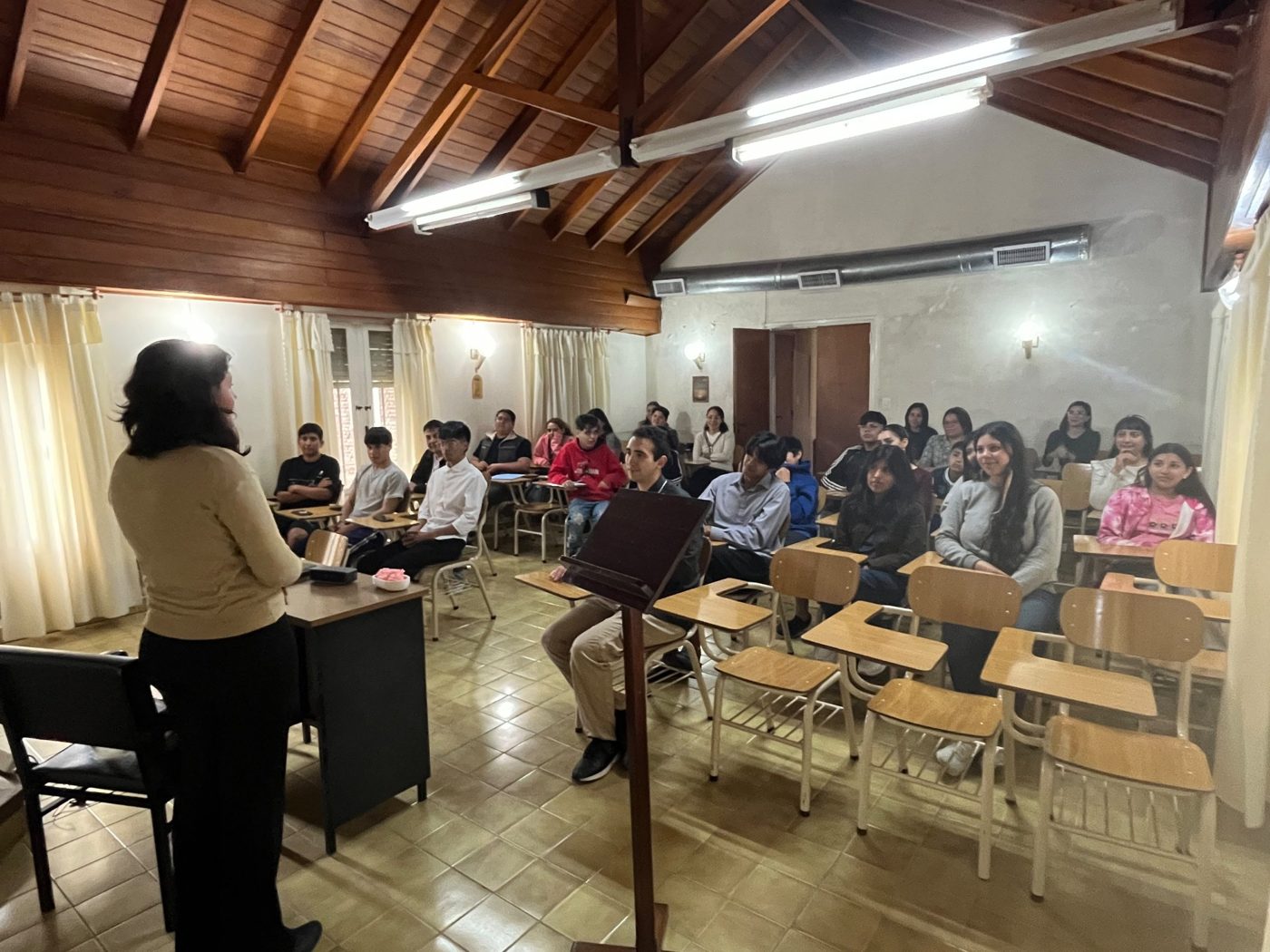 Estudiantes en el aula escuchando a una docente